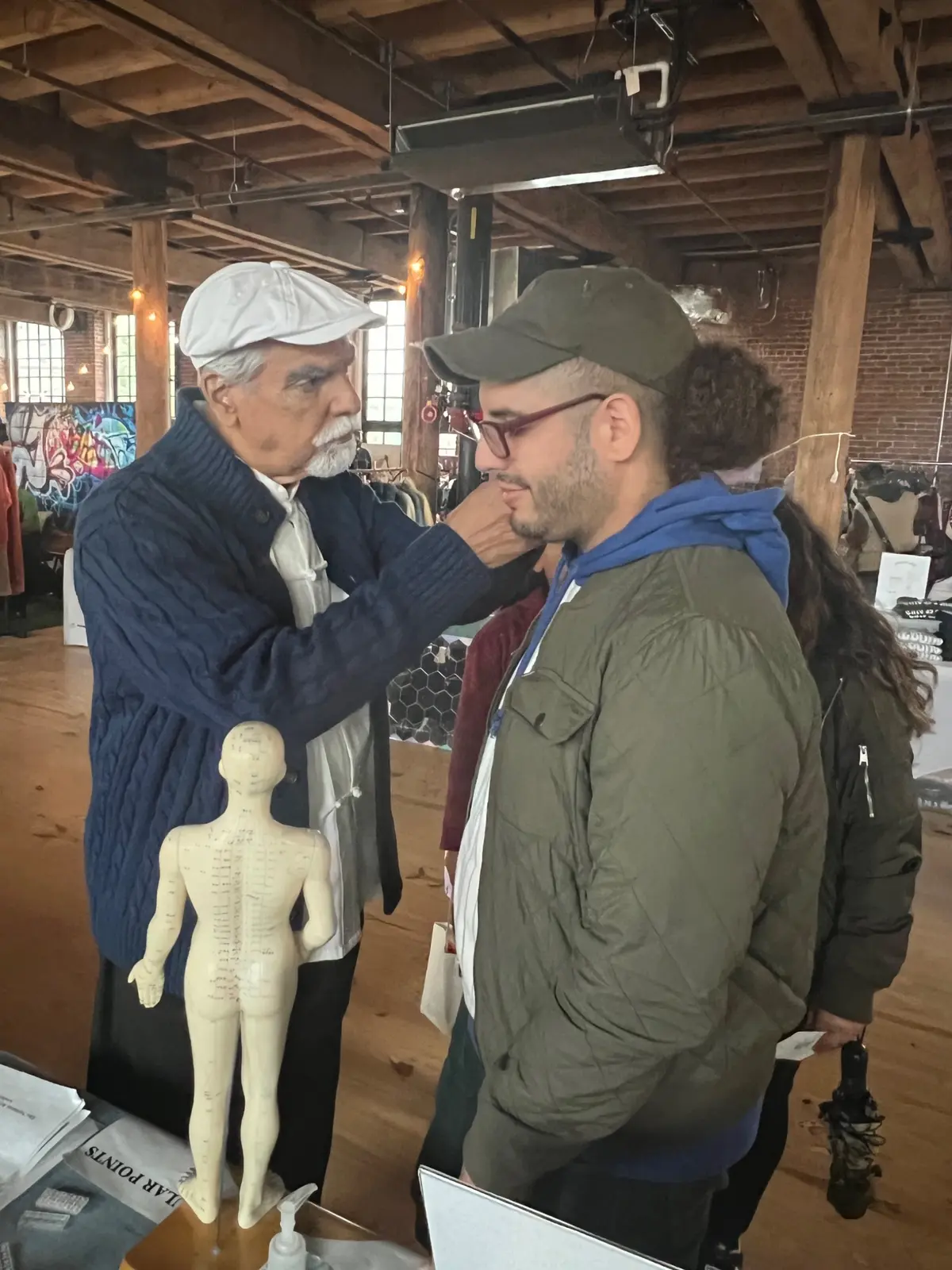 Practitioner demonstrating a technique near an acupuncture model
